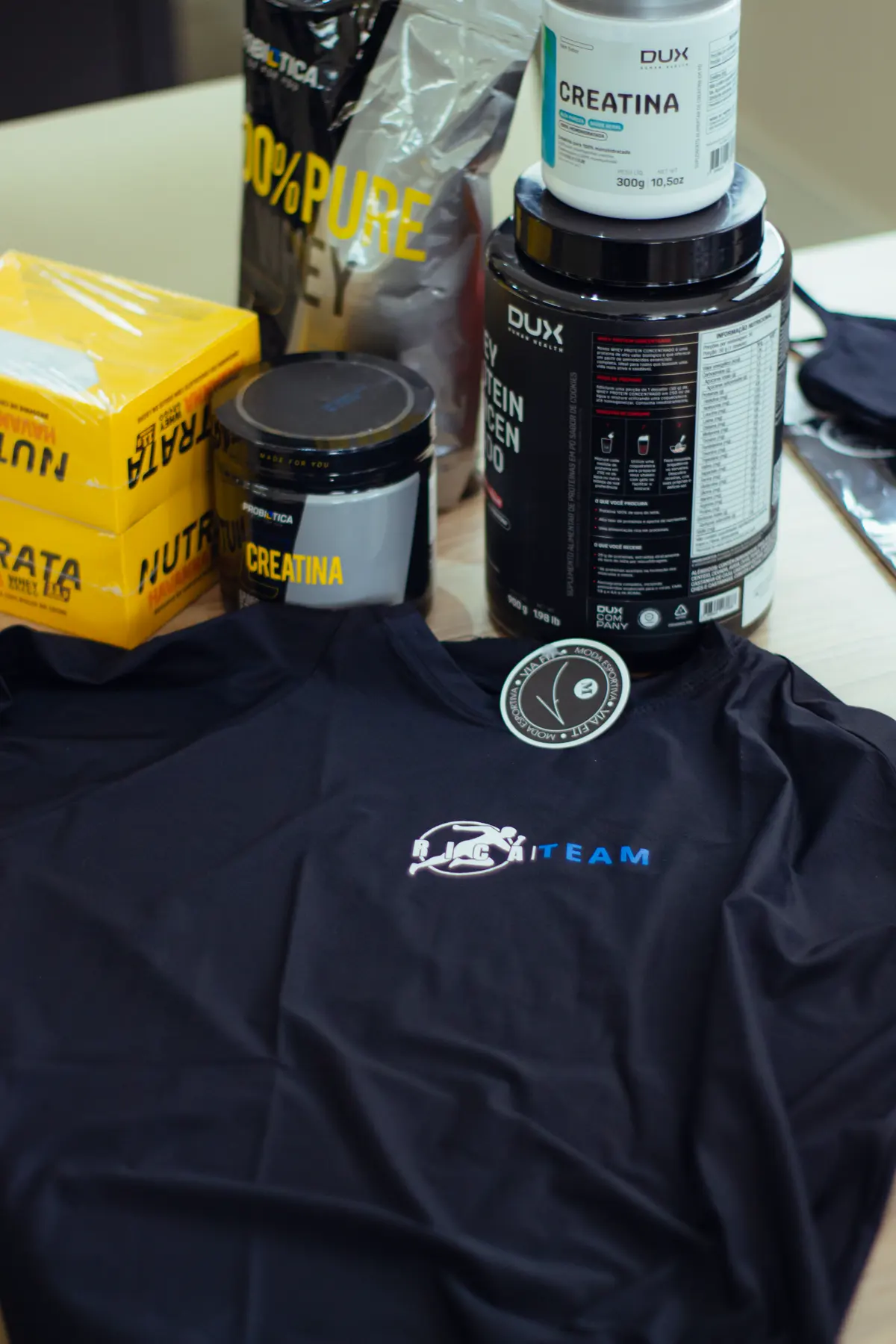 Suplementos e camiseta do Rica Team sobre a mesa
